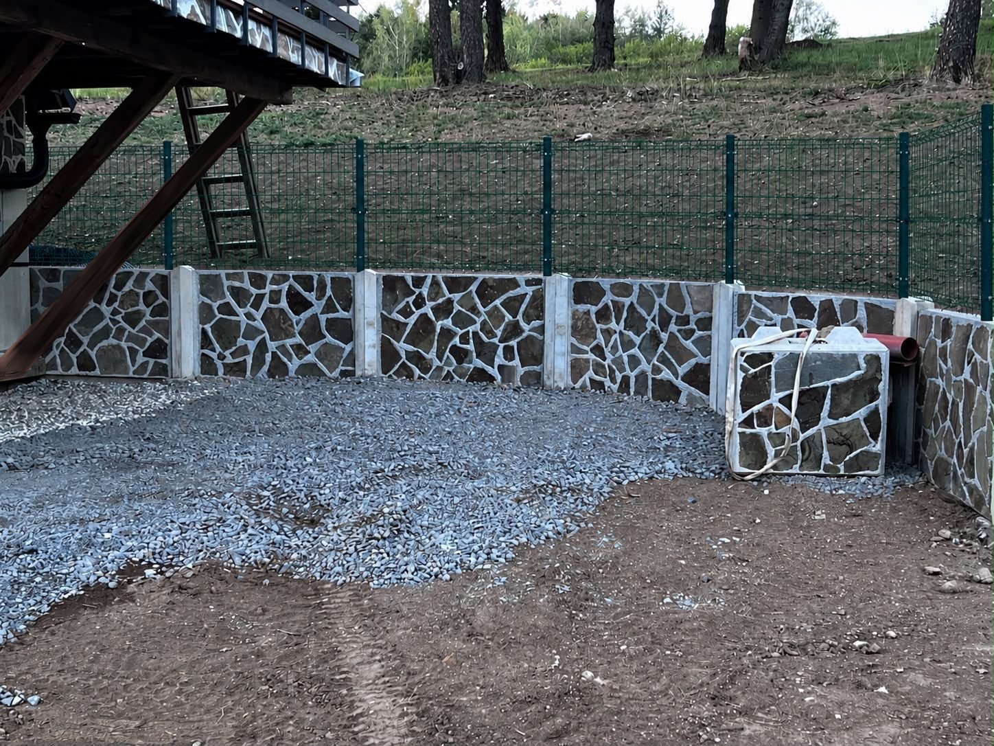 Betónový oporný múr s kamennou úpravou a pletivovým plotom na stĺpikoch uchytených na múre