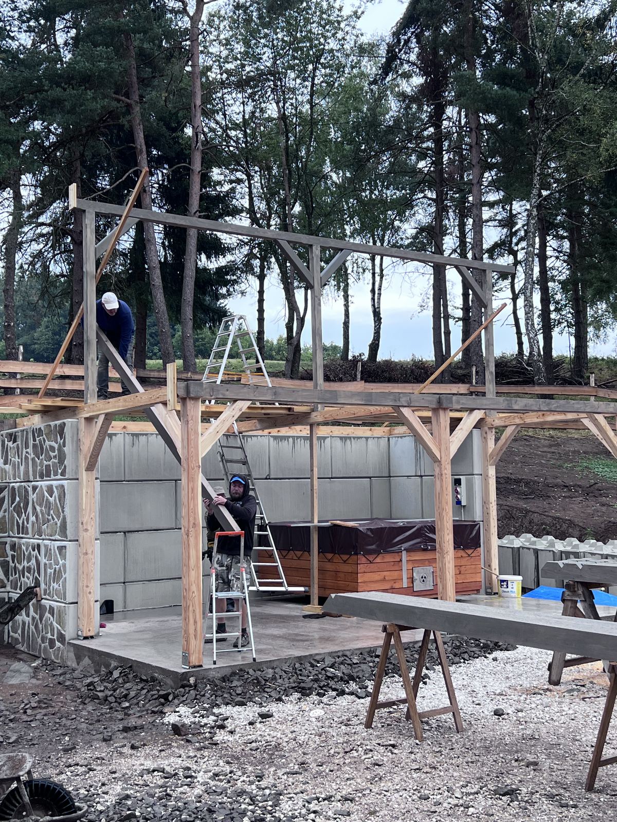 Drevená konštrukcia prístrešku osadená na oporný múr z betónových blokov