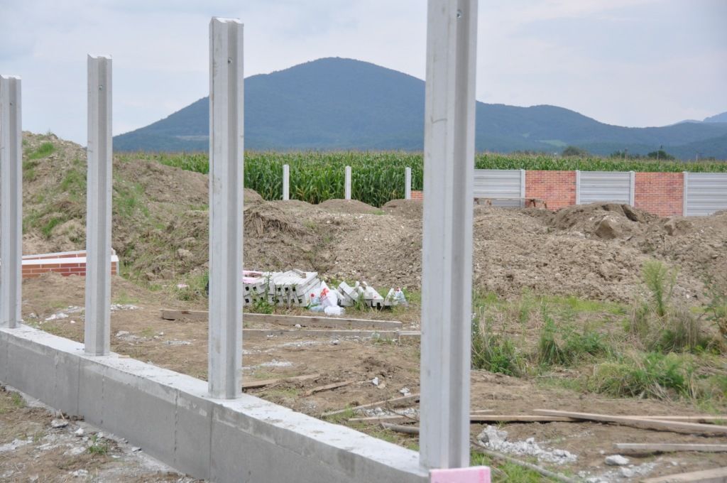 Osadené betónové stĺpiky plota na základovom páse počas montáže